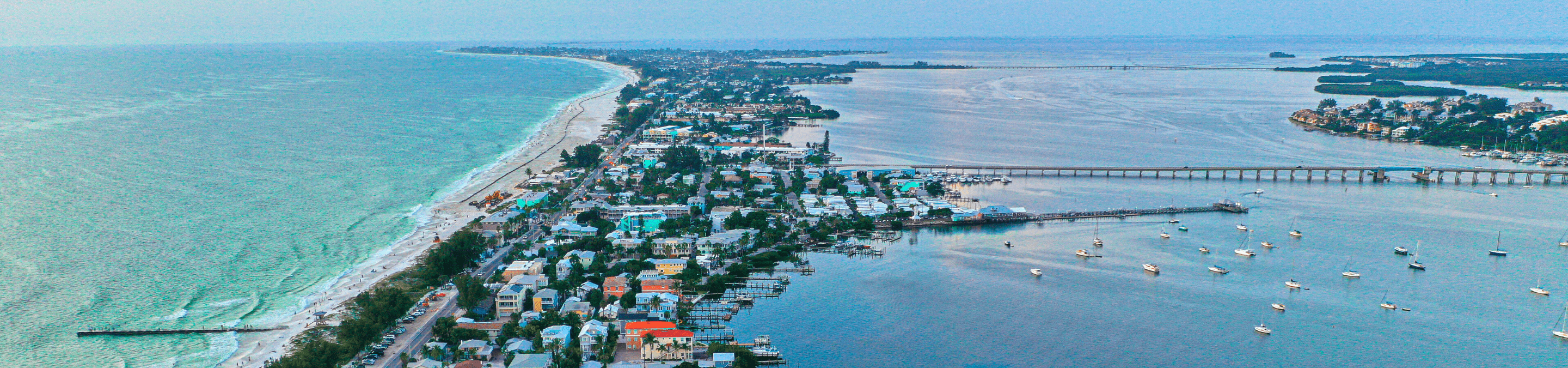 aerial view from drone over Bradenton Beach showing many buildings on the island, the gulf of Mexico on the left and the bay on the right