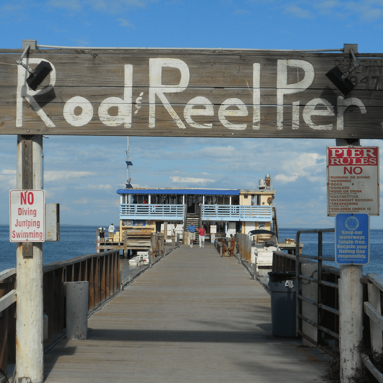 wooden sign showing Rod and Reel Pier in painted white lettering above the walkway leading out to the restaurant at the end of the pier on Anna Maria Island
