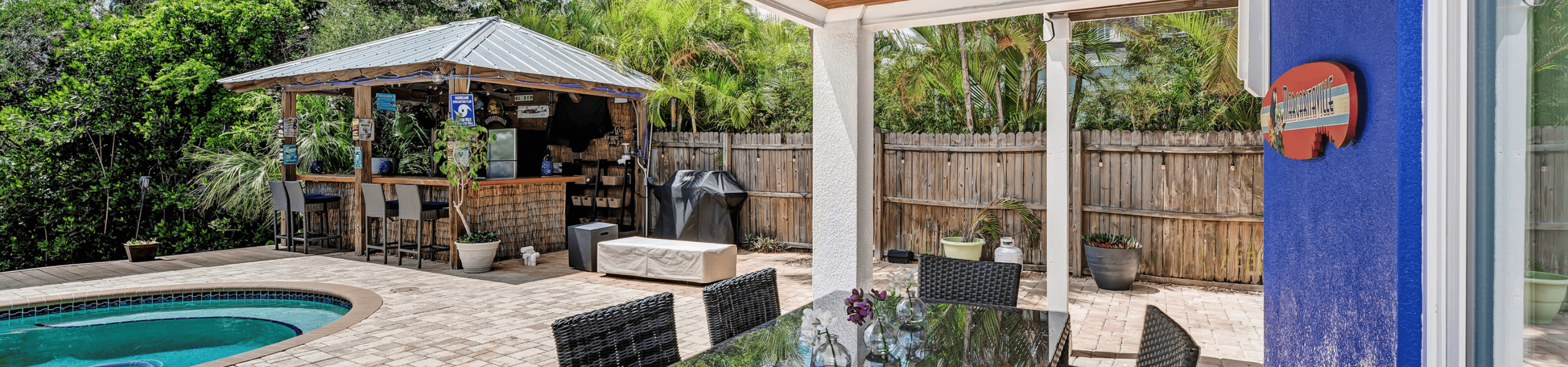 covered patio over a dining table overlooking pool with paver patio and a covered bar on the side of the pool located at our 5 bedroom vacation rental on anna maria island