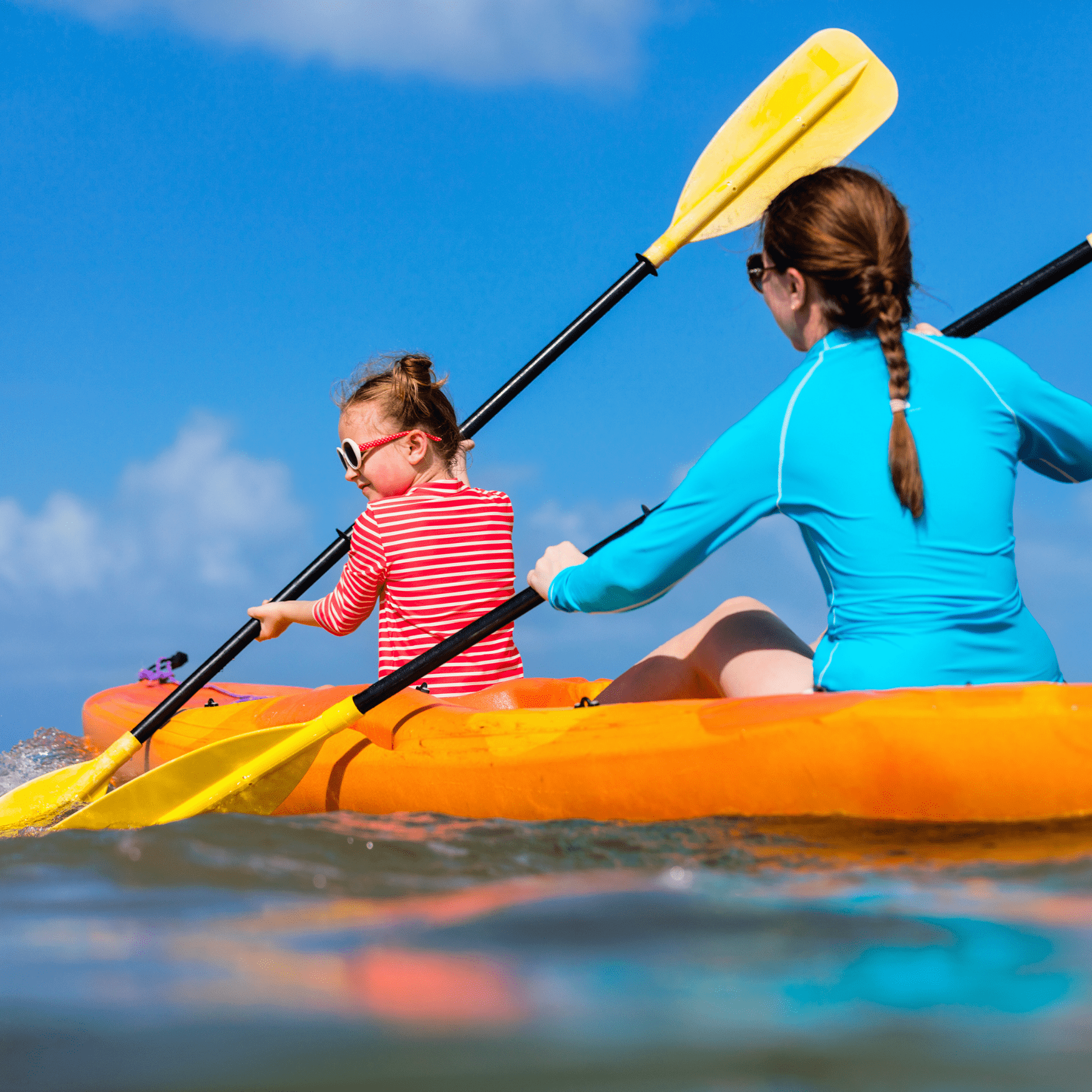 Woman and little girl paddling a two seat kayak.