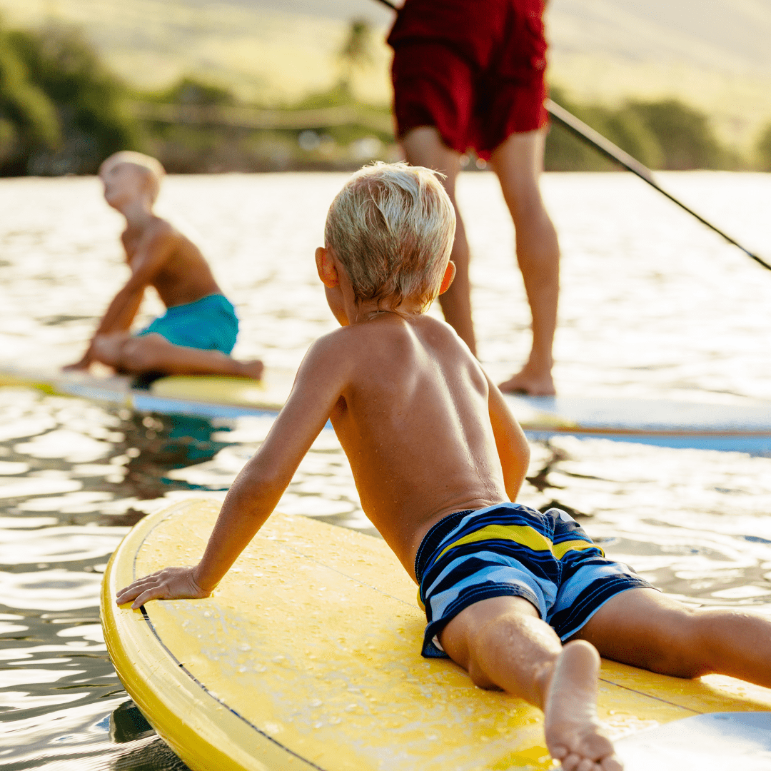 Adult man and two children on stand up paddle boards,