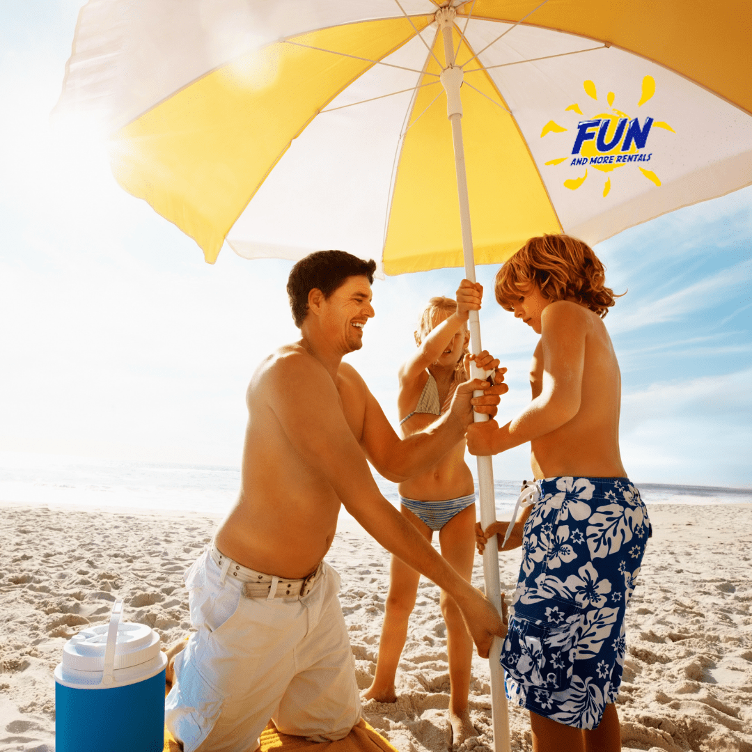 Father and two children setting up a beach umbrella in the sand.