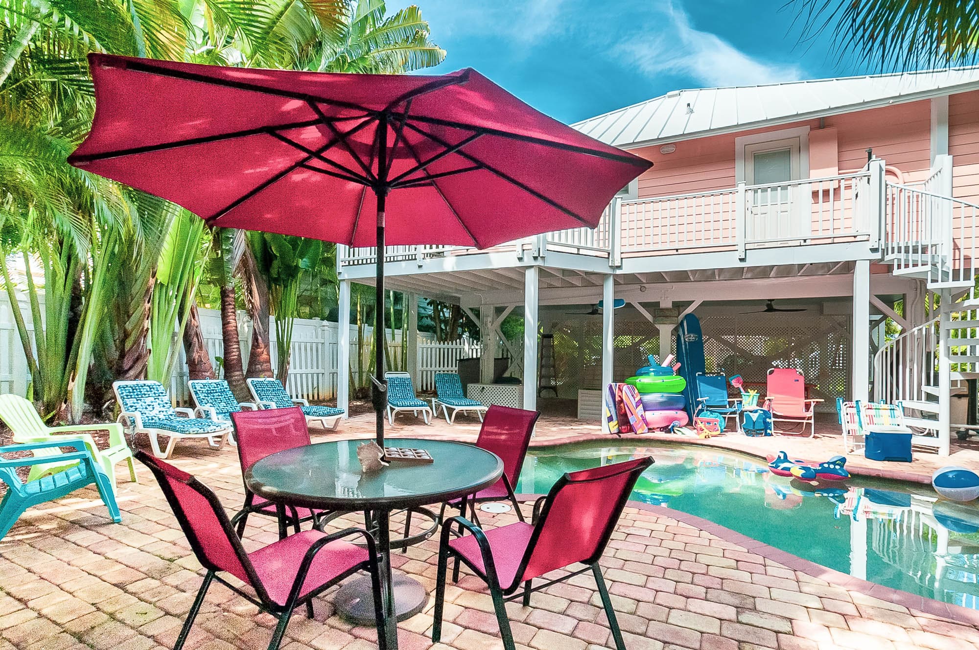 photo of the vacation rental Art n Sol from the back, featuring the outdoor dining area, patio with chairs, pool area as well as beach floats.