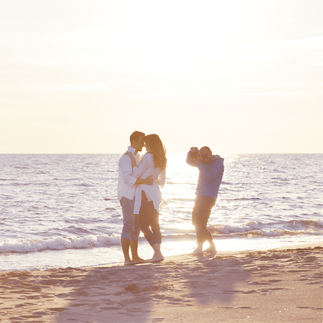 Photographer taking a picture of a couple on the beach.