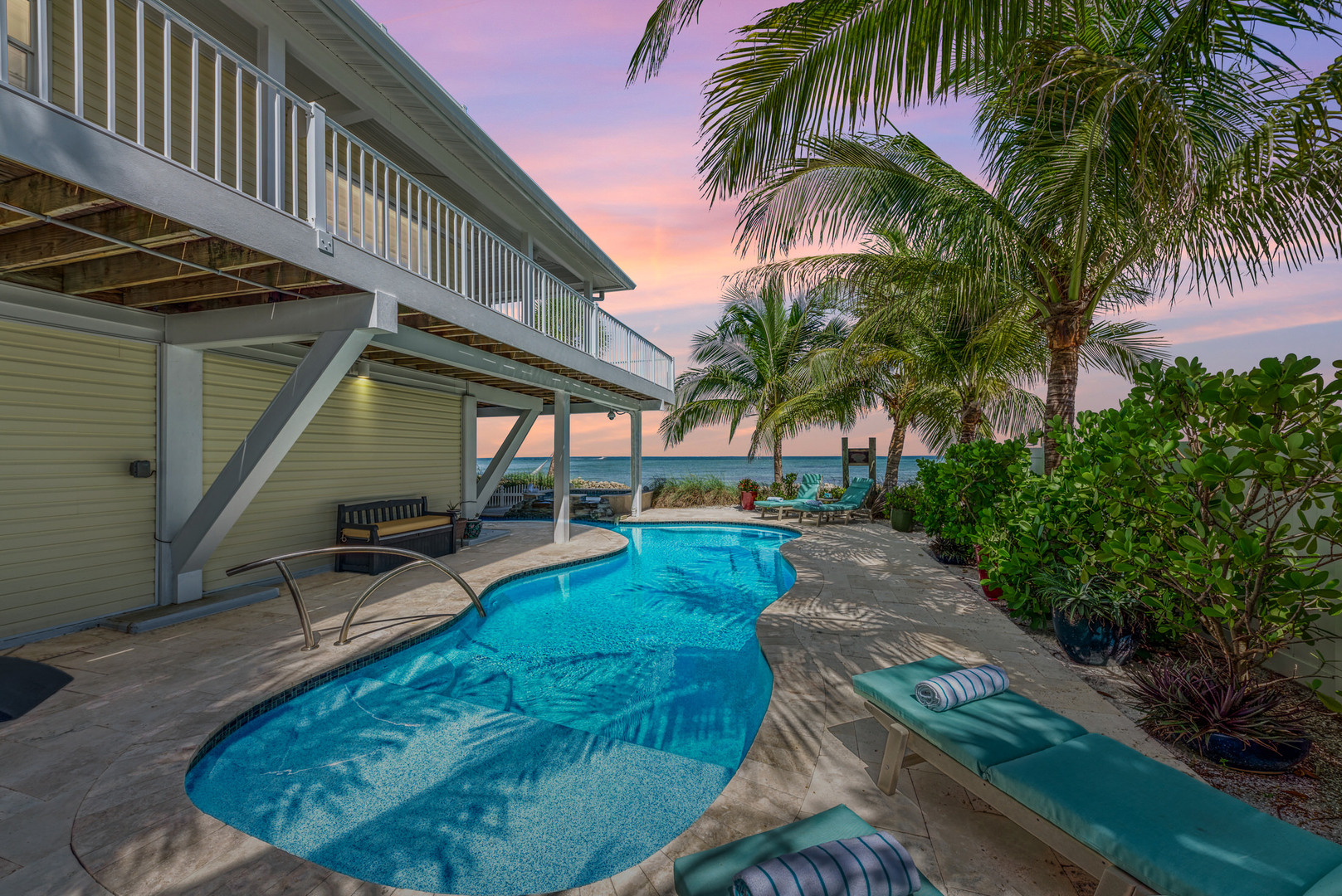 At our Anna Maria island vacation rentals, enjoy pool overlooking the bay at sunset at Dolphin Tales by Anna Maria Life Vacation Rentals
