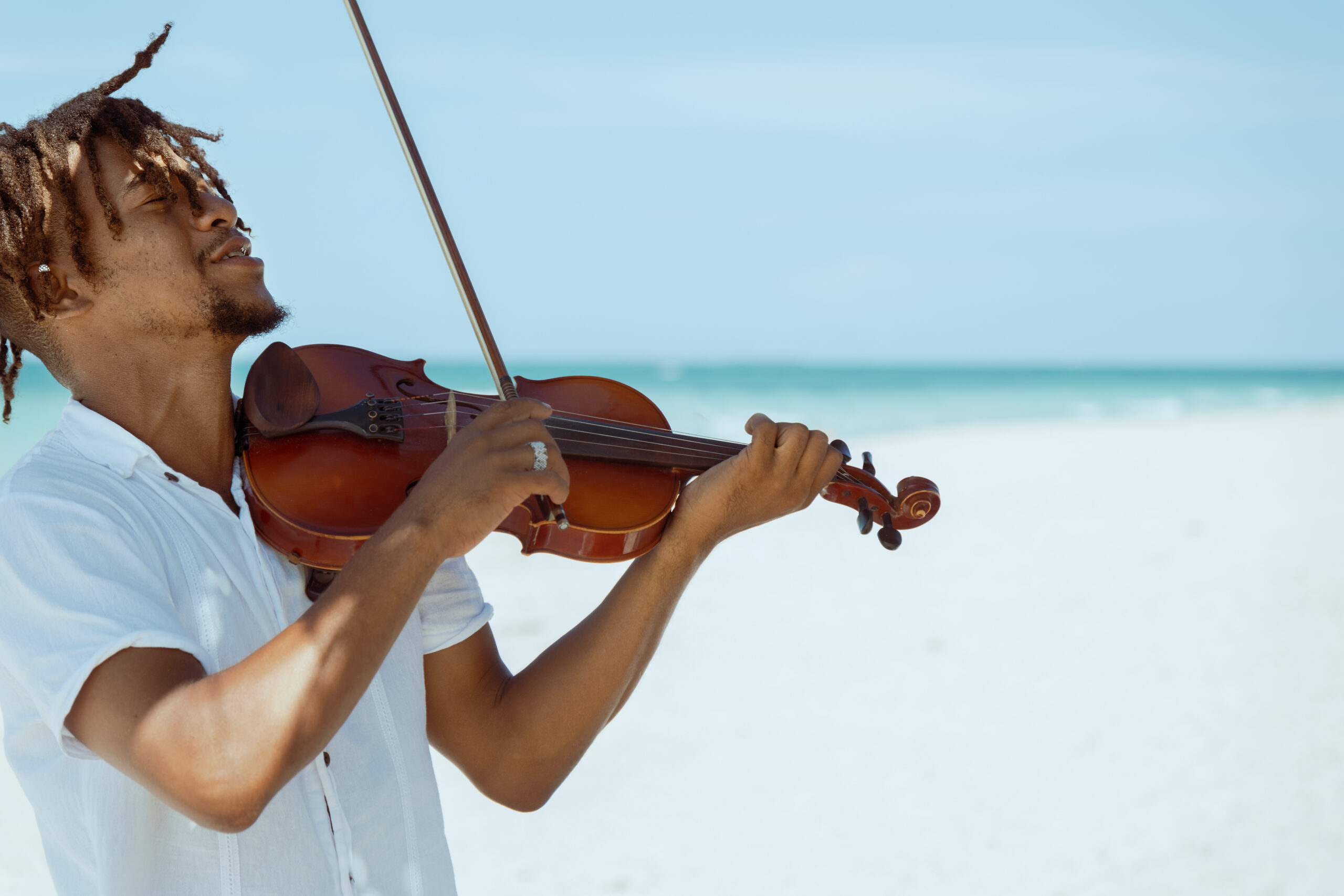 Passionate musician playing violin on the beach